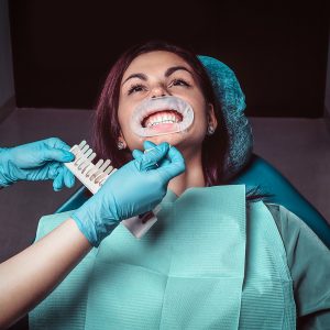 A woman dentist checks the level of teeth whitening in the dentist office.