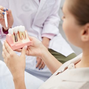 Closeup of unrecognizable female doctor pointing at tooth model while consulting patient, copy space